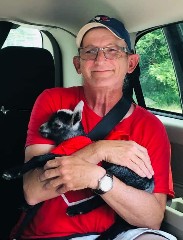 A CLDC client cuddles with a baby goat in the back of a car.