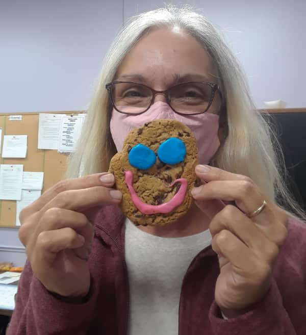 A CLDC employee holds a Tim Hortons smile cookie in front of her mouth.